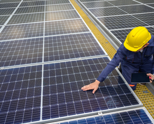 Side view of a man inspecting solar panels